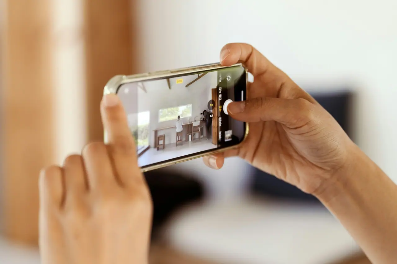 Deux mains photographient une pièce avec un téléphone.